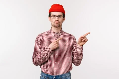 Skeptical serious-looking bothered young geeky man in red beanie and glasses Stock Photos