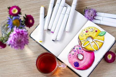 Sketching donuts in notebook. All placed on wooden table with a transparent c Stock Photos
