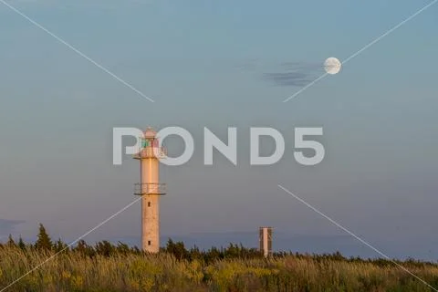 Skew lighthouse in the Baltic Sea. Shore, evening light, sunset, moon and arc Stock Photos