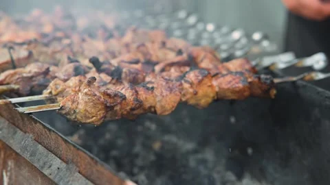 Skewered meat cooks over an open fire . The flames and smoke create atmosphere 스톡 동영상 345031784
