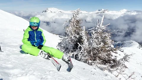 Ski boy sit smiling on top of the mountain covered by clouds Video stock 204139981