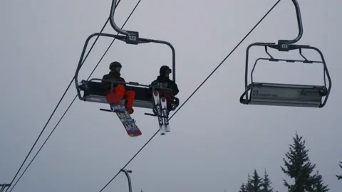 Ski complex, ski lift at a ski resort, two guys riding a ski lift Stock Footage 230883768