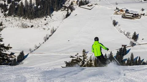Ski driver making a sharp turn on a terrain edge with flying snow at Flach... Stock Photos