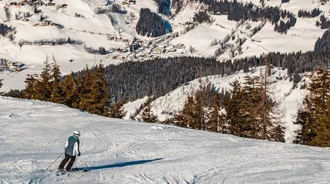 Ski driver making a sharp turn on a terrain edge with flying snow and the ... Stock Photos