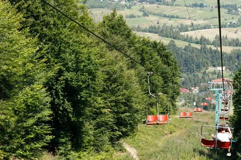 Ski elevator with red chairs moving down. Carpathians Gimba Mountain. Stock Photos