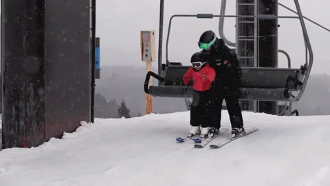 Ski Instructor School helping child off chairlift Stock Footage 221397901
