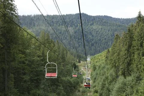 Ski lift and green trees at mountain resort Stock Photos