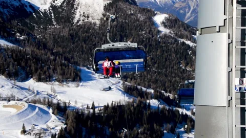 Ski lift chairs passing by while skiers are sitting inside Video stock 141226945