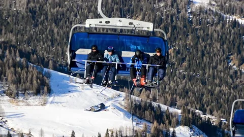 Ski lift chairs passing by while skiers are sitting inside in ski resort. Stock Footage 152688368