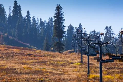 Ski lift chairs in summer on the slopes of the pass, pine trees and brown g.. Stock Photos