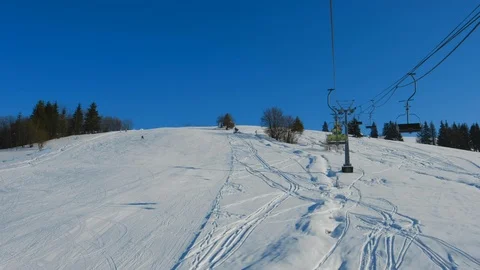 Ski slope with snow surface and skiers lifting on ski-lift in mountains. Stock Footage 112683480
