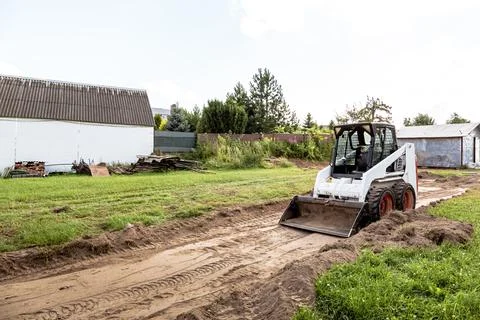 A skid steer loader clears the site for construction. Land work by the territ Stock Photos