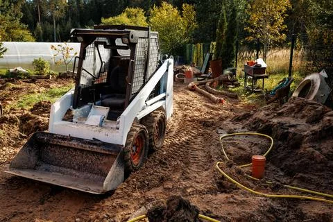 Skid Steer Loader on Dirt Path at Construction Site with Greenhouse Stock Photos