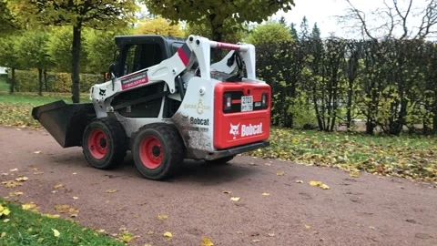 Skid steer loader drives through the park Stock Footage 143732678