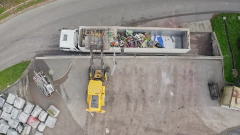 Skid steer loader loading a truck with waste material, aerial top down view Stock Footage 234011953