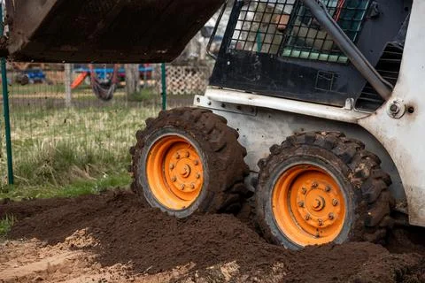 Skid Steer Loader Moving Soil on Uneven Ground with Raised Bucket Stock Photos