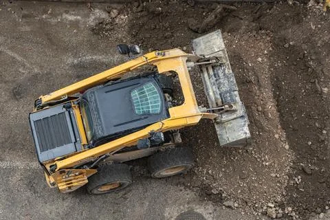 A skid steer loader shovels soil in a park. Construction heavy equipment fo.. Stock Photos