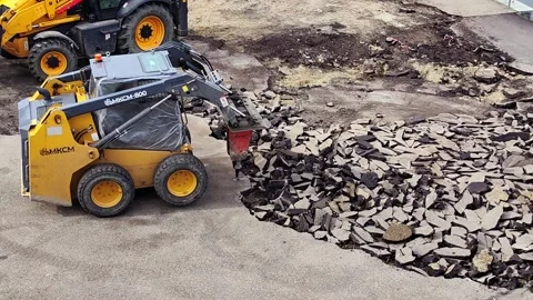 Skid steer loader using hydraulic breaker demolishing asphalt pavement. Video stock 328969073