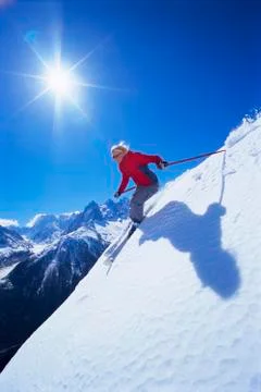 Skier coming down snowy hill smiling (lens flare) Stock Photos