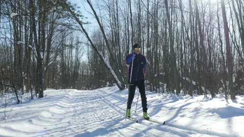 Skier cross-skiing through winter forest in sunny day, 4k steadicam shot Stock Footage 86855909