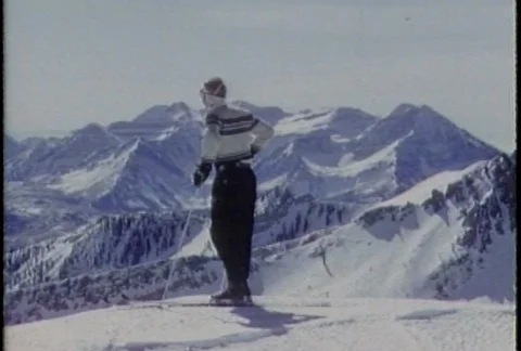 A skier dressed in cool, retro ski clothing stands with ski equipment. Stock Footage 114385295