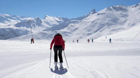 Skier dressed in red skiing moving swiftly across expansive snowy mountain plain Stock Footage 323444355
