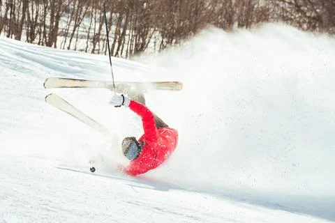 Skier fall down hit head painfully on hard groomed piste with snow swirls o.. Fotos de archivo