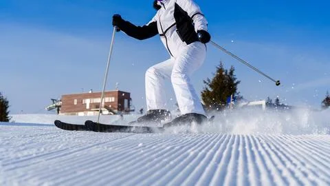 Skier glides gracefully down a pristine snowy slope under a bright blue sky on a Foto stock