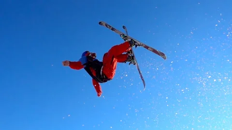 Skier jumping and doing a back flip against blue sky Stock Footage 60937678