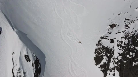Skier leaving tracks on pristine snow field near rocky cliffs Stock Footage 309910635