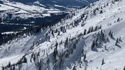 A skier paragliding down a steep face in the Bridger Mountains Stock Footage 236411148