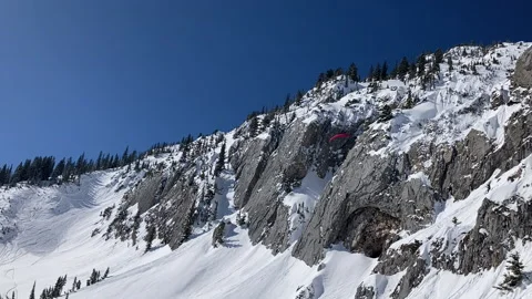 A skier paragliding down a steep face in the Bridger Mountains Stock Footage 236411362