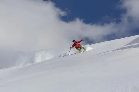 A skier in a red suit makes a sharp turn on a freeride downhill Stock Photos