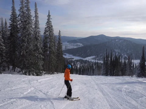 Skier is riding down from the peak of mountain to snowcovered valley Stock Footage 71589964