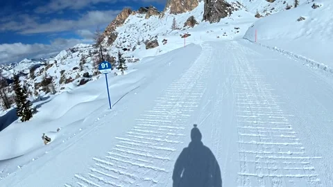 Skier shadow pov skiing down a sunny snowy slope in the dolomites Stock Footage 340624300