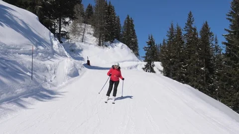 Skier skiing down on snow mountain slope at sunny winter day across pine forest Stock Footage 319901781