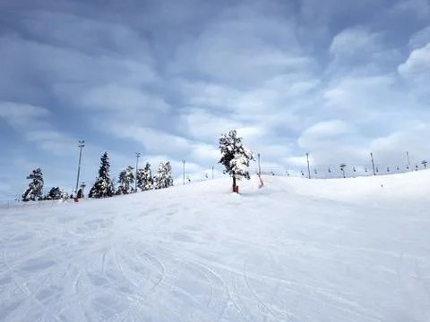 A skier slides down a mountain slope against the background of a sky covered  Stock Photos