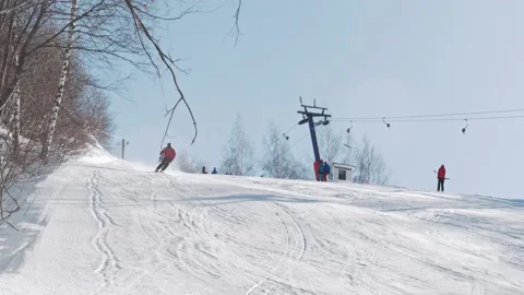 Skier technically carves down the ski slope on a sunny day at a ski resort Stock Footage 221817966