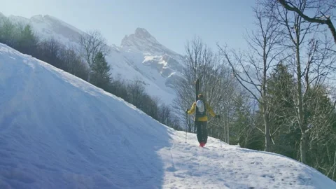 A skier walks with skis on his back to start climbing a mountain, Alps, France Stock Footage 239779836