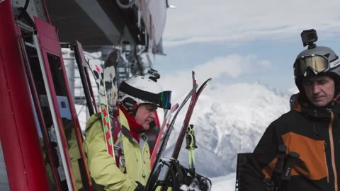 Skiers and snowboarders exit a cable car cabin, ready to hit the slopes with Stock Footage 304502233