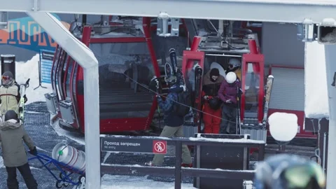 Skiers and snowboarders exit a cable car cabin, ready to hit the slopes with Stock Footage 304739710