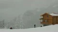 Skiers and Snowboarders Ride Blue Sky Forest Cover Altitude Chalet Cottage Shed HD Footage