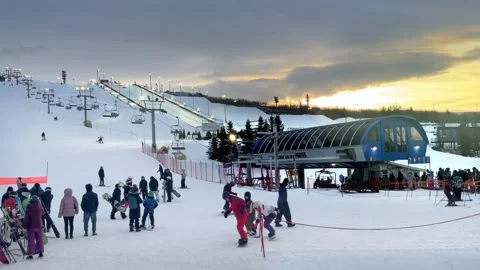 Skiers and snowboarders waiting in a queue at the base of a blue chairlift Stock Footage 326832409
