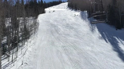 Skiers going down a slope on a sunny day shot from chairlift Park City Utah USA Stock Footage 61863571