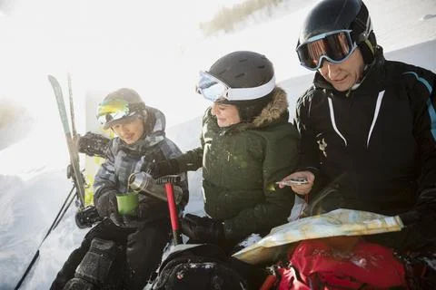 Skiers with map and compass drinking coffee on sunny snowy ski slope Stock Photos