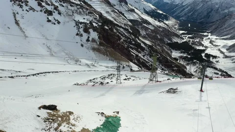 Skiers move fast along steep slopes among snowy mountains Stock Footage 130634713