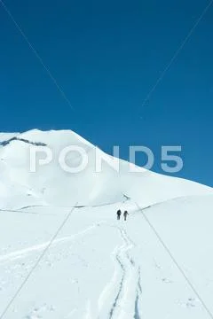 Skiers Moving Uphill In Distance