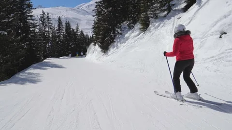 Skiers skiing down sunny alpine terrain amidst scenic beauty Stockbeeldmateriaal 322172867