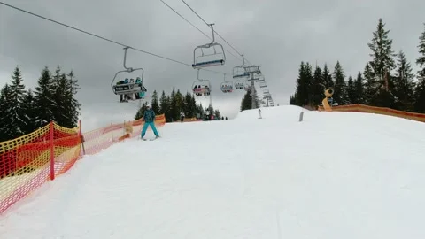 Skiers skiing down under a stopped ski elevator with people Stock Footage 219001671