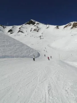 Skiers take the piste down to a ski resort .. Stock Photos